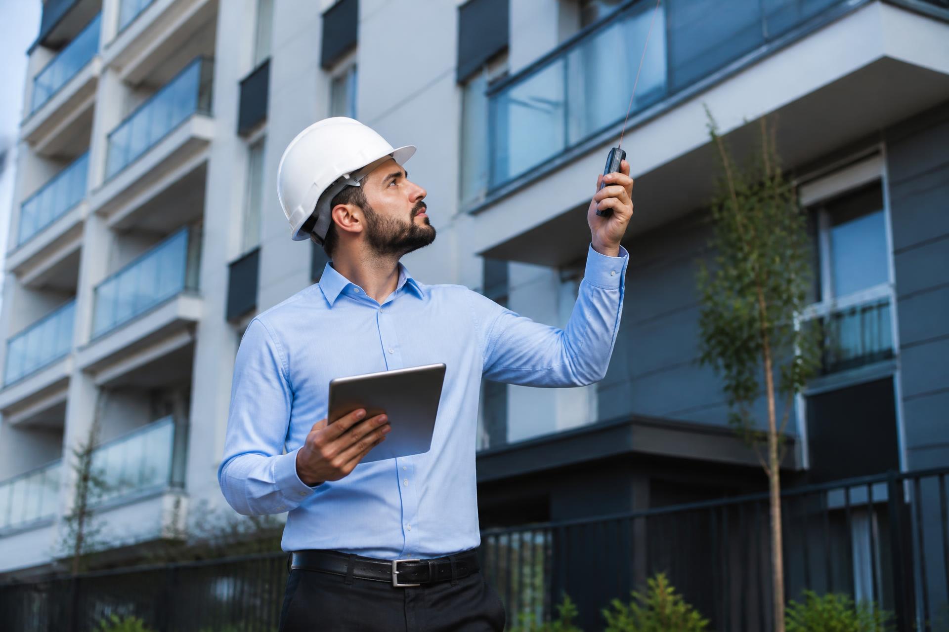 Engenheiro civil realizando vistoria técnica na fachada de um edifício residencial